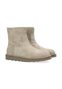 Beige suède enkelboots met een ronde neus, minimale stiksels en een platte rubberen zool. Ontworpen voor eenvoudig aantrekken met een korte hoogte.