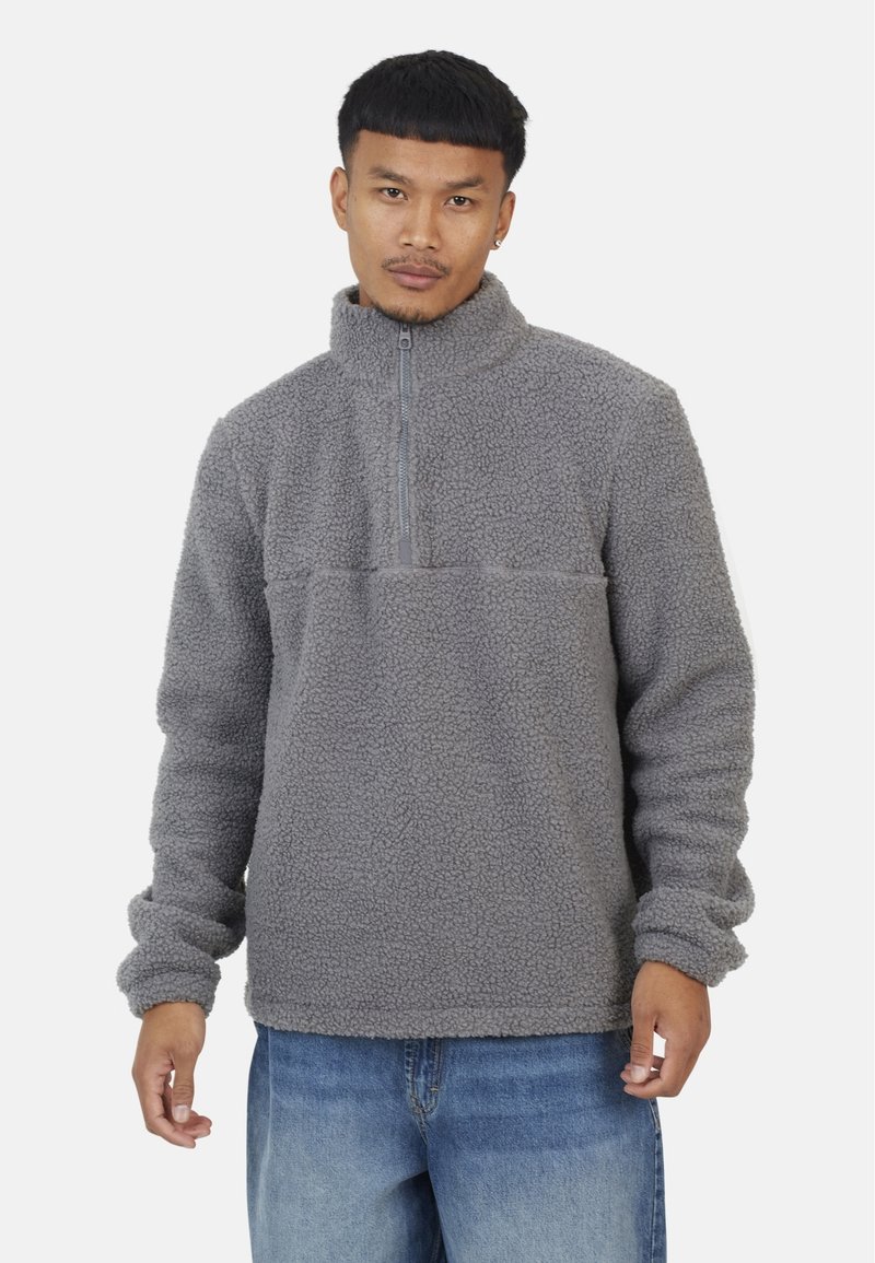 Szary polarowy sweter z pół-zamkiem, o teksturowanej tkaninie, długimi rękawami i poziomą szwem wzdłuż klatki piersiowej. Casualowy design.