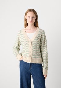 Cardigã tricotado em creme com padrão a zig-zag em verde-agua; apresenta decote em V, punhos canelados e cinco botões decorativos na frente.