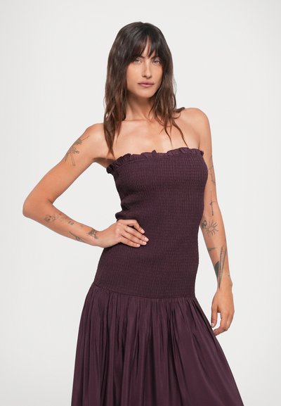 Bordeauxkleurige jurk met een gesmokte strapless corsage en ruches, die overgaat in een geplooide rok. Zachte, gestructureerde stof met een matte afwerking.