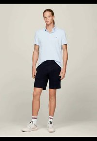 Vaaleansininen polo-paita, tummansiniset shortsit ja valkoiset tennarit punaisilla ja mustilla yksityiskohdilla. Yksinkertainen muotoilu, puuvillamateriaali ja normaali istuvuus.