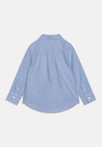 Lichtblauwe blouse met lange mouwen, afgeronde zoom, knoopmanchetten en een rugpasdetail. Gemaakt van een zachte, gestructureerde stof.