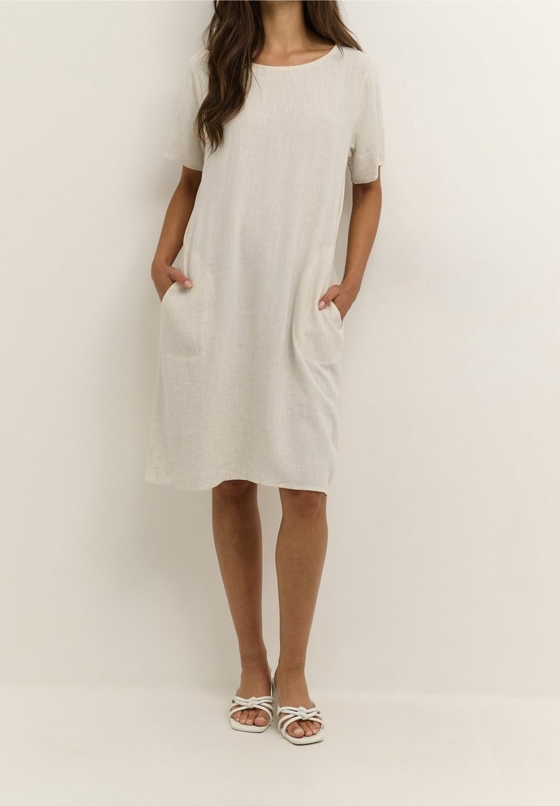 Robe en lin beige clair à manches courtes, col rond et poches latérales. Présente une coupe décontractée et un tissu lisse et texturé.