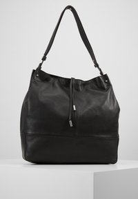 Svart läder tote-väska med en strukturerad yta, justerbar rem, dragsko-stängning och silverfärgade detaljer.