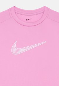 Roze sportshirt van gestructureerde stof, met een wit Nike swoosh-logo op de voorkant. Ronde halslijn met verstevigde stiksels.