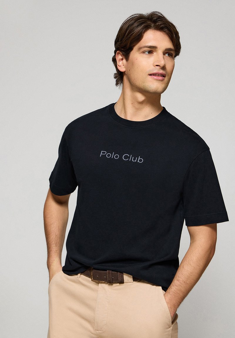 Svart bomull t-shirt med rund halsringning och korta ärmar, med "Polo Club" tryckt i grått över bröstet.