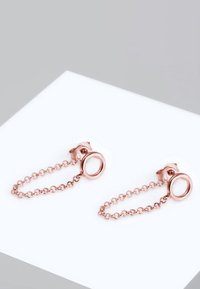 Orecchini pendenti in oro rosa con accenti circolari connessi da una delicata catena, che presentano una superficie metallica liscia e un design minimalista.