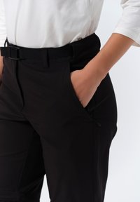 Zwarte broek met een gladde textuur, voorzien van zijzakken, een riemlus en een strak ontwerp. De stof van het kledingstuk lijkt duurzaam en functioneel.