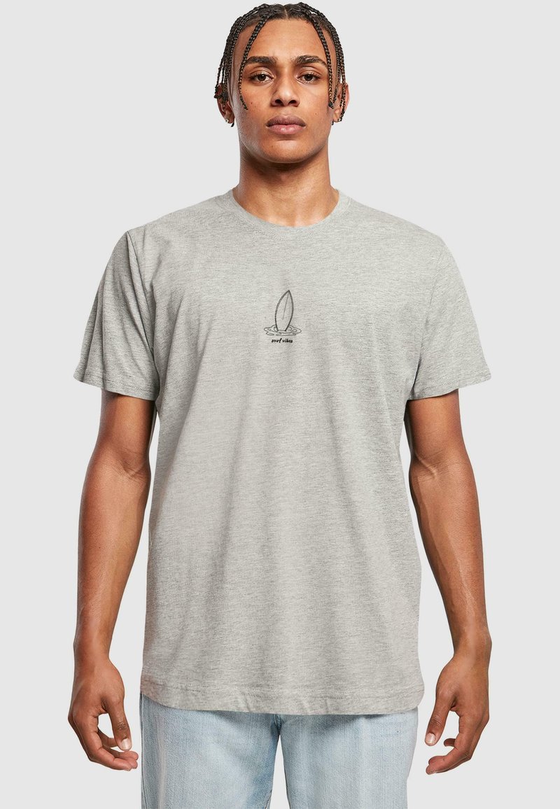 Grå bomulds t-shirt med korte ærmer, med et sort surf ikon grafik i midten. Løs pasform og blød tekstur.