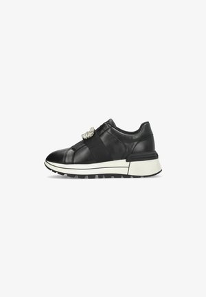Black leather sneaker with elastic strap and rhinestone accent; features a chunky white sole and textured tread for grip.