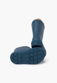 Botas de goma impermeables en azul oscuro, con un suave forro de piel de color marrón claro en la parte superior, suela texturizada con patrones circulares y cuadrados, y una correa lateral.