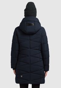 Abrigo acolchado azul marino con capucha, con patrones geométricos en el acolchado y un parche con logo. Fabricado en una tela brillante y suave.