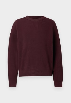 Pull en maille bordeaux avec une texture côtelée, un col rond et des manches longues. Présente une coupe légèrement ample et des fentes latérales à l'ourlet.