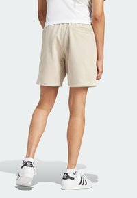 Beiga bomullsshorts med en avslappnad passform, elastisk midja och bakficka. Kombinerade med vita och svarta sneakers.