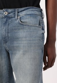 Lichtblauwe denim jeans met een rechte snit, voorzien van een knoop- en ritssluitingen, een vijf-pocket ontwerp en subtiele vervaging over de hele broek.