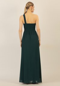 Einseitiges, langes, grünes Abendkleid aus weichem Stoff; besitzt ein gerafftes Oberteil und einen fließenden Rock mit geradem Saum.