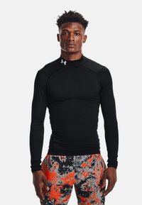 Juodas ilgomis rankovėmis marškinėlis su aukštu apykakle, pagamintas iš lygaus, tamprios medžiagos. Yra "Under Armour" logotipas ant krūtinės.