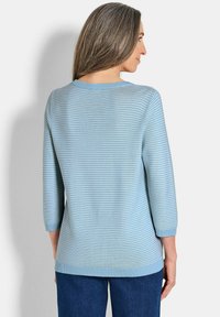 Hellblauer Strickpullover mit horizontalen weißen Streifen, Rundhalsausschnitt und Dreiviertelärmeln. Weicher Stoff und ein gerader Schnitt.