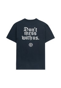 Námořnické bavlněné tričko s velkým bílým potiskem na zádech, na kterém je napsáno "Neruš nás" a s kruhovým logem na spodní části.