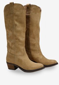 Botas de vaquero de ante color beige hasta la rodilla con punta ligeramente afilada, detalle de costura interior y un tacón bajo de madera.