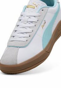 Adidași albi cu accente bleu deschis, capac din suede pe vârf, talpă din cauciuc și branding auriu. Prezintă un design clasic cu șireturi și o textură netedă.