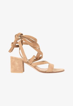 Sandale beige en daim à talon haut bloc, bout ouvert, avec plusieurs lanières autour de la cheville nouées en nœud.