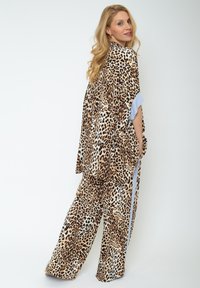 Zestaw dresowy w panterkę z luźną bluzą i szerokimi spodniami. Miękka tkanina z niebieskimi paskami na rękawach i bocznych szwach.