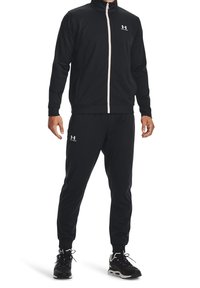 Black athletic tracksuit featuring a zip-up jacket with high collar, pink zipper, and matching pants. Made from smooth, stretchable fabric.