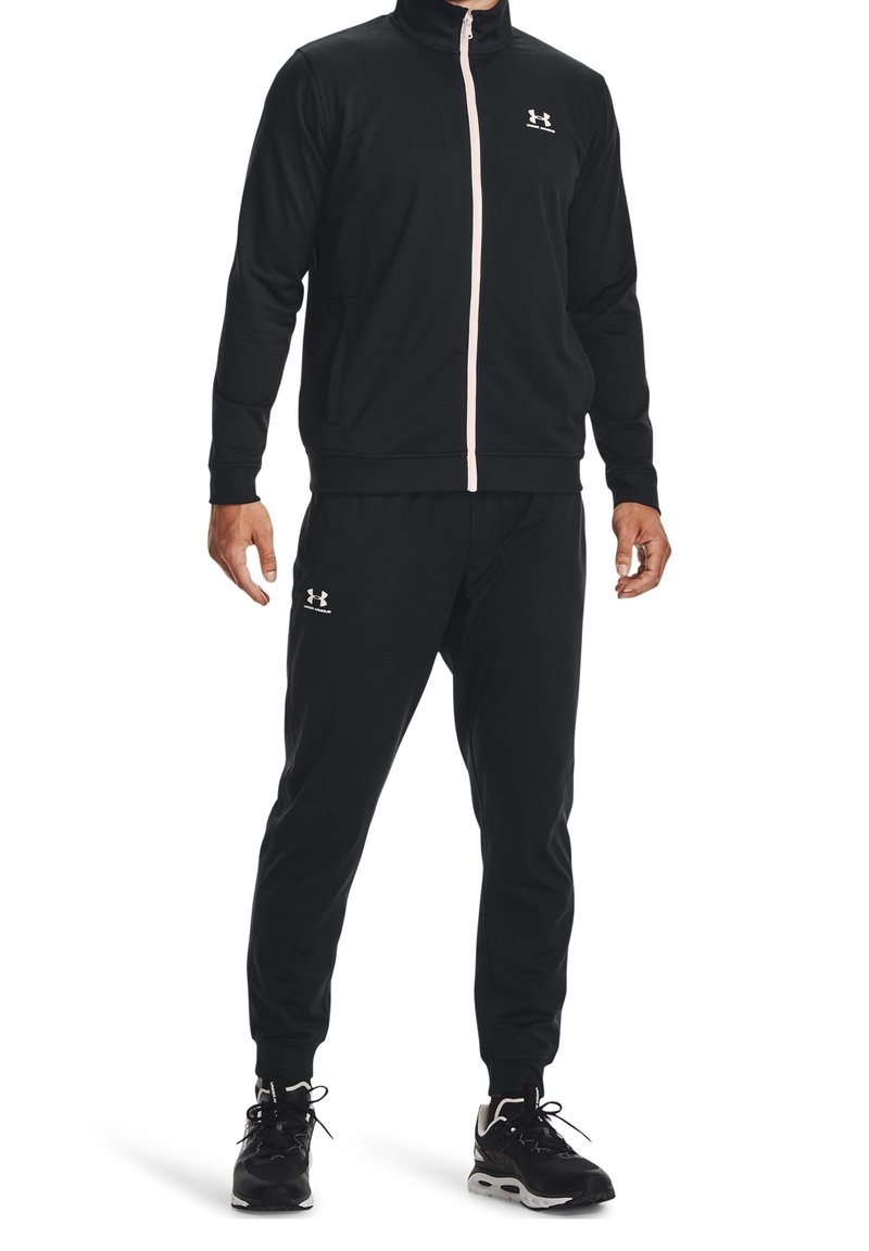 Black athletic tracksuit featuring a zip-up jacket with high collar, pink zipper, and matching pants. Made from smooth, stretchable fabric.