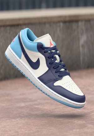 Niskie sneakersy z granatowymi, jasnoniebieskimi i białymi panelami, granatowymi sznurówkami, logo Nike i czerwonym logo Jumpman na języku i pięcie.