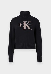 Pull en maille bleu marine avec un col montant, des poignets et un ourlet côtelés. Présente un grand logo brodé rose clair "CK" ainsi que le texte "calvin klein".