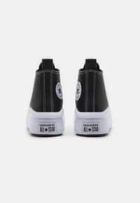 Sneakers alte nere con finitura texturizzata, suola in gomma bianca e patch circolare con logo su ciascun tallone. Dettagli con cuciture a contrasto.