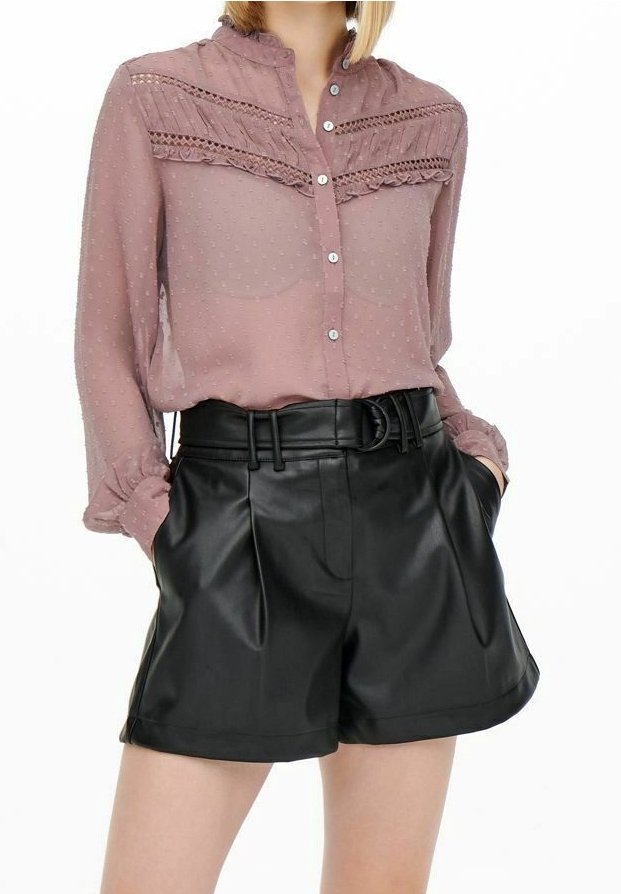 Light mauve, long-sleeved blouse with textured polka dots and lace trim, paired with black high-waisted faux leather shorts featuring a belt.