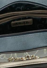 Helles blaues strukturiertes Lederbeutelintern mit mehreren Fächern, silberner Hardware und einem dunklen gemusterten Futter. Es verfügt über dekorative Nähte.