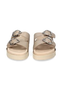 Two beige sandals with wide straps, featuring silver buckles and a soft, cushioned sole; minimalistic design with a sturdy base.