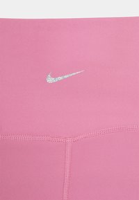 Leggings Nike cor de rosa com um material elástico suave. Detalhes notáveis incluem um logo Nike refletivo e costuras planas para maior conforto.