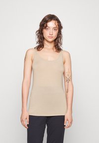 Beige ribbed tank top with wide shoulder straps, featuring a fitted design and a smooth texture.⠀⠀