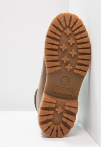 Bruine Timberland-bootzool van robuust, gestructureerd rubber, met een patroon op de zool voor grip en het Timberland-logo in het midden gedrukt.