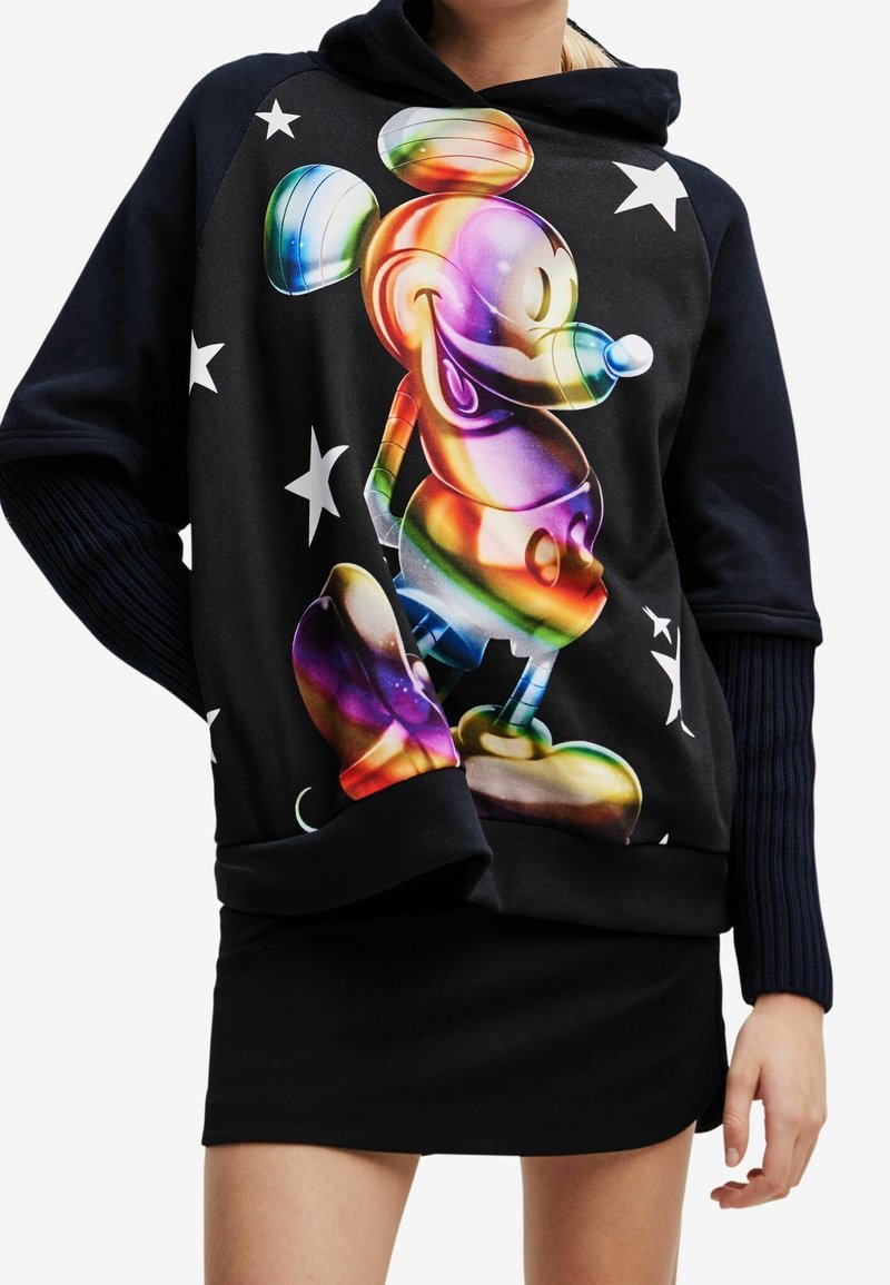 Sudadera negra con capucha que presenta un gráfico colorido de Mickey Mouse con acentos de arcoíris, rodeado de estrellas blancas. Detalle de mangas acanaladas visible.
