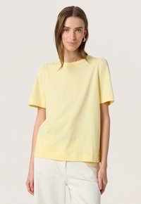 Tricou galben cu mânecă scurtă, cu guler rotund și mâneci ușor bufante, având o textură de bumbac neted și o croială lejeră.