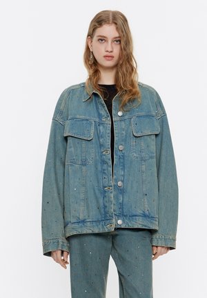 Jeans jakna, svetlo modra, oversize kroj, vsebuje dva žepa na prsih, srebrne gumbe in razpršene večbarvne bleščice na tkanini.