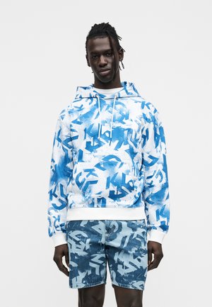 Leichter blau-weißer Kapuzenpullover mit abstrakten Mustern, ausgestattet mit einem Kordelzug an der Kapuze und gerippten Bündchen, kombiniert mit passenden Jeansshorts.