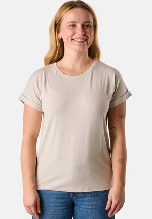 Light beige short-sleeve t-shirt with a round neckline, rolled sleeves, and a soft, smooth texture, paired with blue denim jeans.