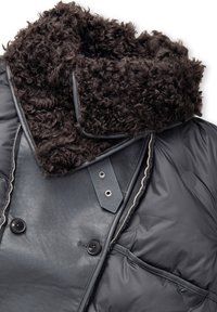 Czarna skórzana i ocieplana kurtka zimowa z kręconym sztucznym futrem na kołnierzu i dużymi czarnymi guzikami.