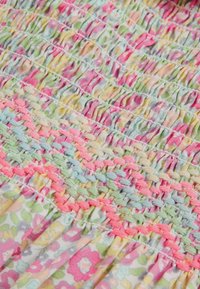 Floraler Stoff mit Raffung in Pastellfarben, darunter Rosa, Grün und Hellblau; filigrane gewebte Details erzeugen ein strukturiertes Muster.