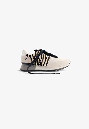 Baskets beige clair avec des accents en noir et imprimé zèbre. Dotées d'une tige en suède texturé, de lacets noirs et d'une semelle en caoutchouc grise.