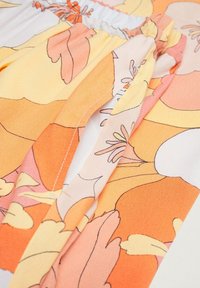 Tissu à motif floral en orange, rose et blanc. Matériau léger avec une texture lisse et élastique froncée à la taille.