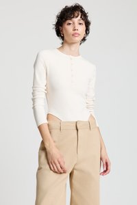 Body en crème à manches longues avec encolure ronde et fermeture à boutons, associé à un pantalon beige taille haute. Tissu doux et coupe ajustée.