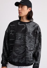 Black sweatshirt with gray printed designs including classical motifs and a bold text. Features a round neck and ribbed cuffs.