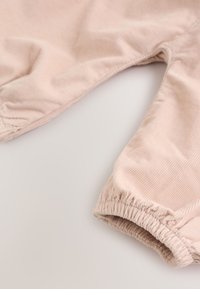 Light beige corduroy pants with elastic cuffs, shown flat on a neutral background.